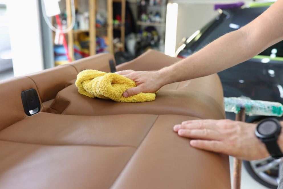 Een schoonmaker die een bruine leren bank schoonmaakt met een gele handdoek tonen bank reinigen in Castricum